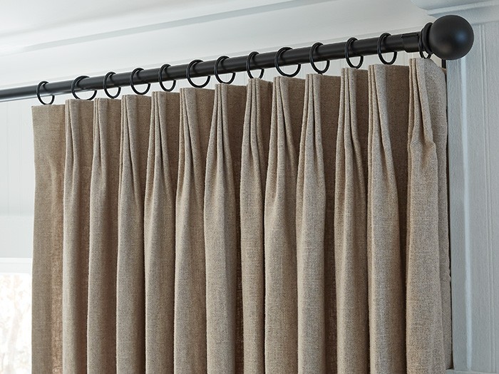 Beautiful brown linen drapery hanging on a black curtain rod. 
